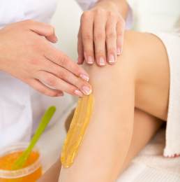 The beautician uses uses her manicured fingers to rub hot wax into the woman's CGI-generated leg_